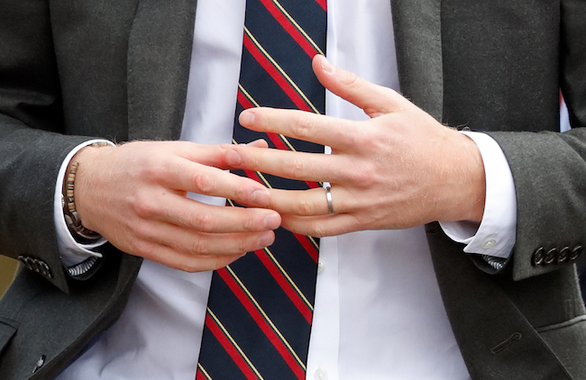 Nervous hands of suited man with wedding band.