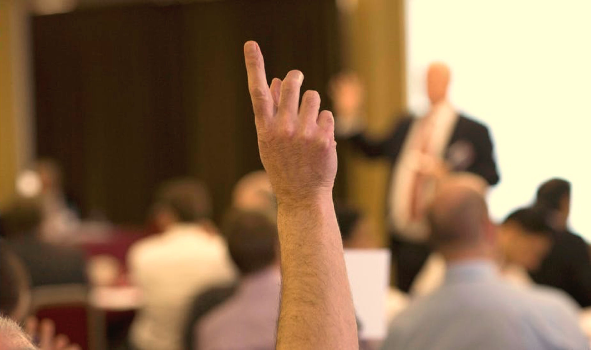 Hand in the air gesturing question at public speaking conference